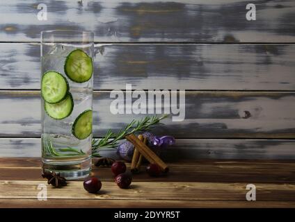 Nahaufnahme eines isolierten Cocktailglases mit Gin Tonic Gurkenscheiben, Zimt, Lavendel, Rosmarin, Cranberries Botanicals. Holzbretter mit Kopie-Spac Stockfoto