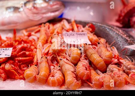 Frischer Krabbelfisch im Vordergrund mit Garnelen und Seehecht Der Hintergrund aus dem Fokus auf einen Fischmarkt in Valencia mit dem Preis im Hintergrund Stockfoto