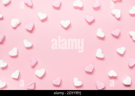 Weiße und rosa herzförmige Marshmallows auf einem rosa Hintergrund mit Kopierraum. Stockfoto