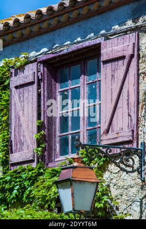 Rustikales Hausfenster mit hölzernen Fensterläden. efeu und Laterne in Südfrankreich Stockfoto