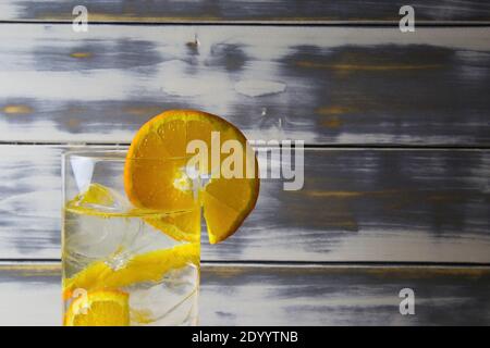 Nahaufnahme von isolierten Cocktail-Glas mit Gin Tonic Orange Obst Scheiben und Eiswürfel. Holz alten vintage Planken mit Copy Space Hintergrund. Stockfoto