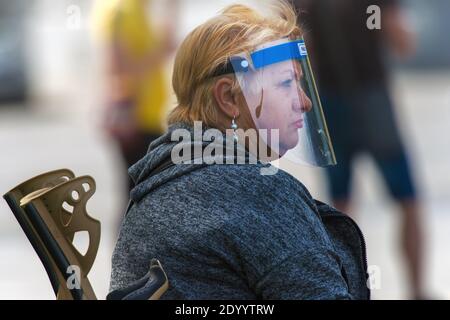 Frau trägt einen Kunststoff-Gesichtsschutz als Schutz vor dem Corona-Virus und anderen luftgetragenen Partikeln und Krankheiten. Stockfoto