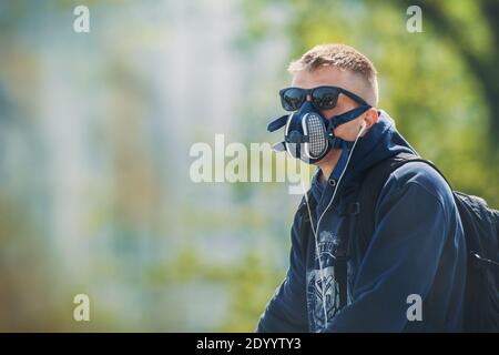 Der junge Mann trägt eine N99 Atemschutzmaske und Sonnenbrille. Der Mann schützt sich vor Coronavirus und anderen luftgetragenen Partikeln und Krankheiten. Stockfoto