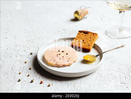 Traditionelle französische Foie Gras, Lebkuchen, kandierte Zwiebel im Teelöffel auf der weißen Platte auf dem hellen Hintergrund Stockfoto