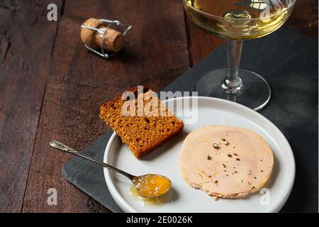 Traditionelle französische Foie Gras, Lebkuchen, kandierte Zwiebel im Teelöffel und ein Glas Champagner auf dem dunklen Tisch Stockfoto