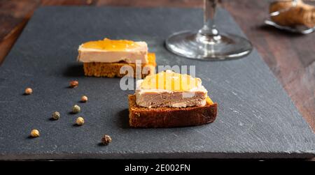 Foie Gras Vorspeise mit kandierten Zwiebeln und Pfefferkörnern auf einem Schiefer Stockfoto