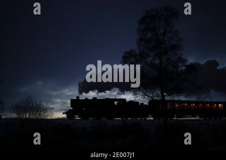 Kidderminster, Großbritannien. Dezember 2020. Trotz des erheblichen Schneefalls in der Grafschaft Worcestershire heute, nichts hält die Severn Valley Railway in ihren Spuren! Diese traditionsreiche Dampfeisenbahn hat die Passagiere den ganzen Tag über mit alten Zügen begeistert, die durch das umliegende Winterwunderland dampfen. Eine der letzten Dampfzüge des Tages ist hier zu sehen, nach Sonnenuntergang, die auf der Rückfahrt vorbeischnuppern. Kredit: Lee Hudson/Alamy Live Nachrichten Stockfoto