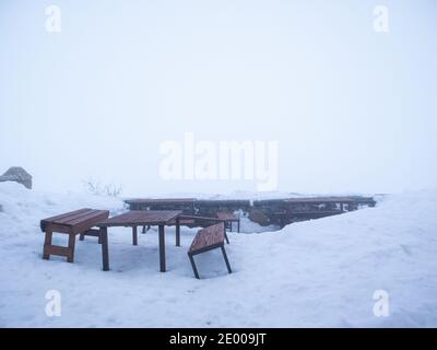 Zwei Holzbänke und ein Tisch im Schnee mit Ein nebliger Himmel Stockfoto