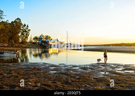 Junge Mädchen, die ihren Hund am Strand bei Sonnenuntergang, Rainbow Beach, Queensland, QLD, Australien