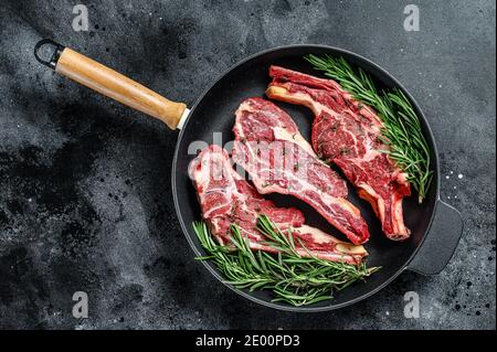 Auswahl an rohen Fleischstücken Rindfleisch Steaks in einer Pfanne. Schwarzer Hintergrund. Draufsicht Stockfoto