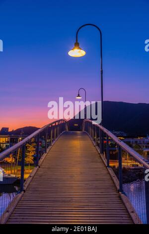 Blick auf den Sonnenuntergang über einer Holzbrücke, die zum Yachthafen in Picton, Neuseeland führt Stockfoto