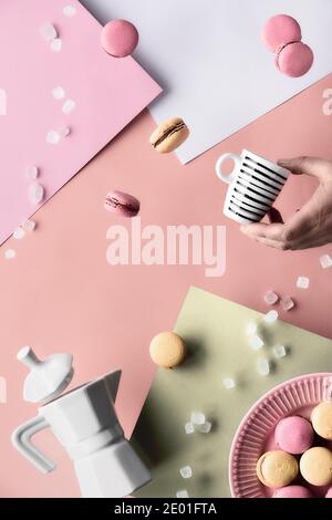 Levitation und Balance Komposition mit fliegenden Objekten. Makronen, Keramik-Kaffeemaschine und Hand mit Espresso-Tasse. Hintergrund für geschichtetes Papier in Stockfoto