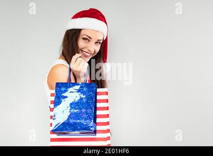 Glücklich lachende Frau in Weihnachtsmann Hut hält Weihnachtsgeschenk Pakete. Hochformat mit leerem Kopierbereich Stockfoto