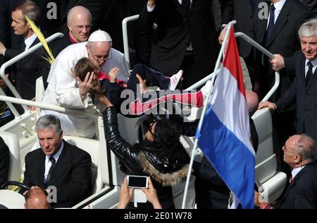 Papst Franziskus feiert am 24. März 2013 seine erste Palmsonntagsmesse auf dem Petersplatz im Vatikan, während die Gläubigen mit Begeisterung Olivenzweige und geflochtene Palmwedel winken. Am Ende der zweistündigen Messe kletterte Franziskus in ein offenes Papemobil, um durch die begeisterte Menge zu kreisen. Er lehnte sich aus, um die Hände zu schütteln, küsste und klopfte die Köpfe von Säuglingen, die ihm von Leibwächtern übergeben wurden, und gab den Kindern oft das Daumen-hoch-Zeichen. Papst Franziskus wurde von der Zeitschrift Time zur Person des Jahres ernannt. Während seiner neun Monate im Amt hatte der Papst "das Papsttum aus dem Palast gezogen Stockfoto