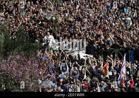 Papst Franziskus feiert am 24. März 2013 seine erste Palmsonntagsmesse auf dem Petersplatz im Vatikan, während die Gläubigen mit Begeisterung Olivenzweige und geflochtene Palmwedel winken. Am Ende der zweistündigen Messe kletterte Franziskus in ein offenes Papemobil, um durch die begeisterte Menge zu kreisen. Er lehnte sich aus, um die Hände zu schütteln, küsste und klopfte die Köpfe von Säuglingen, die ihm von Leibwächtern übergeben wurden, und gab den Kindern oft das Daumen-hoch-Zeichen. Papst Franziskus wurde von der Zeitschrift Time zur Person des Jahres ernannt. Während seiner neun Monate im Amt hatte der Papst "das Papsttum aus dem Palast gezogen Stockfoto