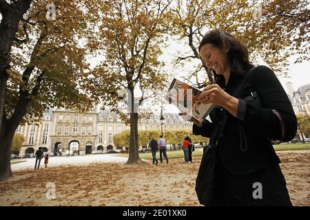 FRANKREICH / Iie-de-France/Paris/ Le Marais /Frau mit Fremdenführer am Place des Vosges, gesäumt von eleganten Stadthäusern. Stockfoto