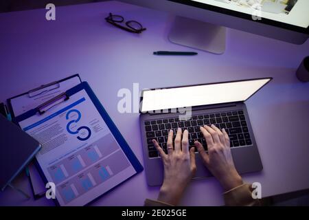 Von oben gesehen Aufnahme von weiblichen Händen tippen etwas auf Laptop in dunklen Büroraum, Kopierer Platz Stockfoto