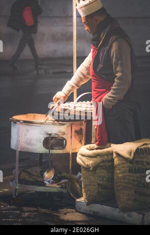 Rom, Italien - 6. November 2014: Ein Straßenhändler röstet Kastanien an einem dunklen, kalten Abend in Rom, Italien Stockfoto