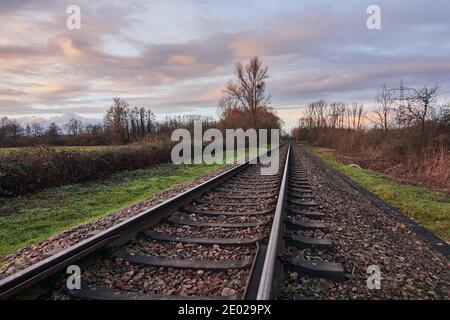 Bahngleise in einer ländlichen Szene, die in fernen Sonnenuntergang führt. Stockfoto