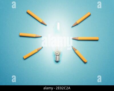 Eine glühende Glühbirne mit 6 Bleistiften als Lichtstrahlen, Neue Ideen oder Kreativitätskonzept auf blauem Hintergrund, Geschäftskonzept Stockfoto