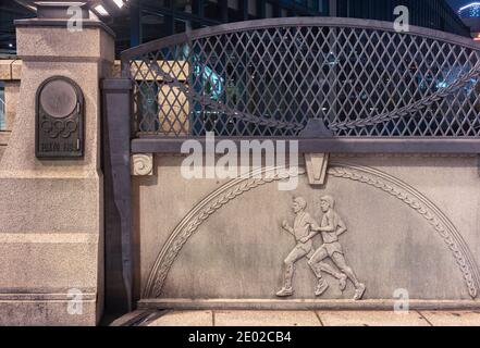 tokio, japan - november 02 2020: Nahaufnahme von gusseisernen Reliefs, die Athleten und Olivenkranzmotive auf der Olympischen Brücke von Harajuku namens Gori zeigen Stockfoto