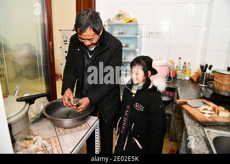 (201229) -- BIJIE, 29. Dezember 2020 (Xinhua) -- Li Changde und seine Enkelin Li Qingyi bleiben in der Küche ihres neuen Hauses in einer neu erbauten Gemeinde zur Armutsbekämpfung Umzug in Shexiang alten Township des Dafang County, südwestlich von Chinas Provinz Guizhou, 23. Dezember 2020. Li Siyu, 8, und seine 6-jährige Schwester Li Qingyi lebten früher im Dorf Hetou als Mitglieder eines von Armut heimgesuchten Haushalts. Sie mussten jeden Tag fast eine Stunde zur Schule gehen. Ihre Eltern arbeiteten in anderen Städten und Li Changde, der 68-jährige Großvater, übernahm die Verantwortung, sie zu und zu bringen Stockfoto