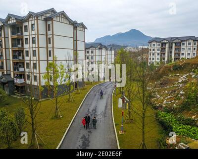 (201229) -- BIJIE, 29. Dezember 2020 (Xinhua) -- Li Changde (C) nimmt seine Enkel Li Siyu (R) und Li Qingyi mit, um in einer neu erbauten Gemeinde zur Armutslinderung in der alten Gemeinde Shexiang im Bezirk Dafang, südwestlich von Chinas Provinz Guizhou, zur Schule zu gehen, 24. Dezember 2020. Li Siyu, 8, und seine 6-jährige Schwester Li Qingyi lebten früher im Dorf Hetou als Mitglieder eines von Armut heimgesuchten Haushalts. Sie mussten jeden Tag fast eine Stunde zur Schule gehen. Ihre Eltern arbeiteten in anderen Städten und Li Changde, der 68-jährige Großvater, übernahm die Verantwortung, sie zu übernehmen Stockfoto