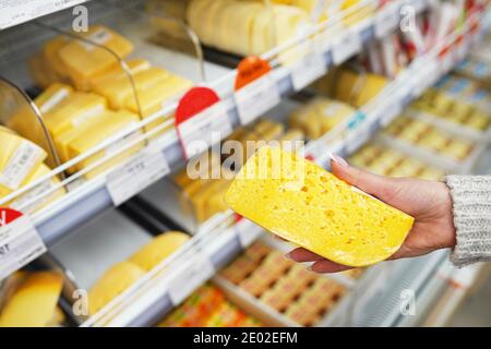 Hand des Käufers mit einem Stück Käse im Store. Stockfoto