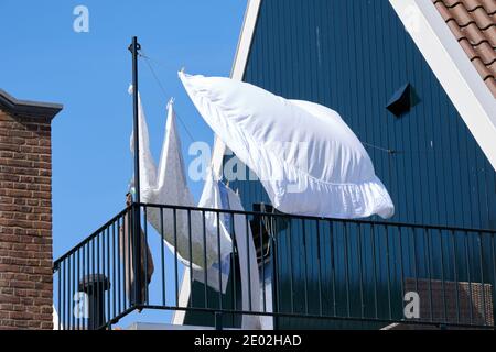 Auf einem Balkon eines blauen Hauses hängt eine Wäscheleine mit Kleidung und Laken, um im Wind zu trocknen Stockfoto