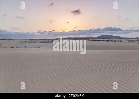 Sand, Dünen und vulkanische Berge bei Sonnenuntergang Landschaft im Naturpark von Corralejo, Fuerteventura, Kanarische Inseln, Spanien. Stockfoto