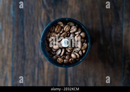 Kaffeebohnen in Kaffeemühle oder Grinder auf Holztisch. Fertig zum Grinden. Stockfoto