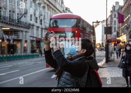 Asiatischer Tourist, der ein Selfie auf Piccadilly während der Tier4 Coronavirus Lockdown in Central London, England, Großbritannien macht Stockfoto