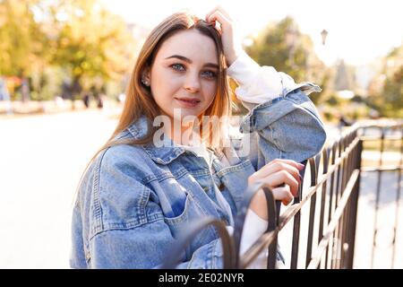 Portrait von inspirierten kaukasischen Mädchen mit trendigen Make-up auf der Straße. Außenfoto einer lächelnden schüchternen Frau mit hellbraunen Haaren, die in der Stadt herumläuft Stockfoto