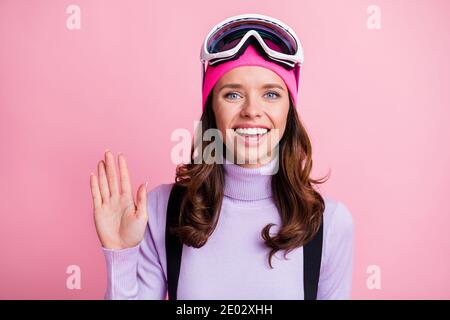 Foto-Porträt von lächelnden glücklichen Frau winken Hand isoliert auf Pastellrosa Hintergrund Stockfoto