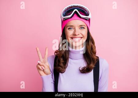 Foto-Porträt von fröhlichen Mädchen zeigt V-Zeichen isoliert auf Pastell Rosafarbener Hintergrund Stockfoto