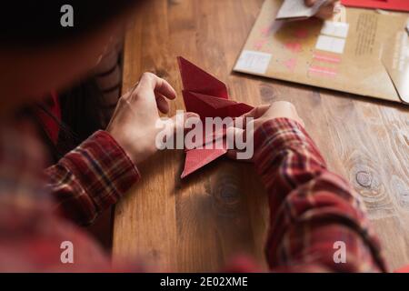 Unkenntlich Frau trägt rot kariertes Hemd mit farbigem Papier Origami-Kran, High-Angle Medium Nahaufnahme zu machen Stockfoto