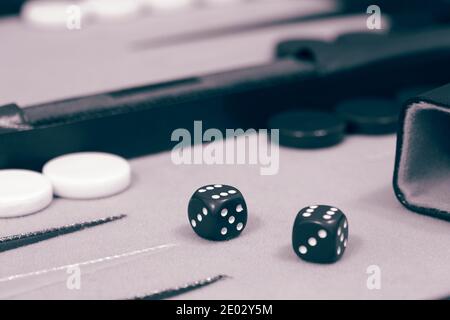 Backgammon-Set, bereit, Spiel zu starten, auf einem Tuch und Lederbrett. Mit Farbtonung Stockfoto