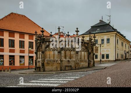 Steinbrunnen im historischen Stadtzentrum mit gepflasterten Straße, bunten Fassaden, Kutna Hora, Tschechische Republik.UNESCO-Weltkulturerbe.Tschechische Popula Stockfoto