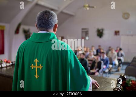 Katholischer Priester steht auf einem Kirchenpodium und predigt, Religion Stockfoto