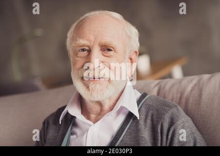 Foto von positiven schönen alten Mann lächelnd Sofa im Inneren sitzen Innen Wohnung Haus Stockfoto