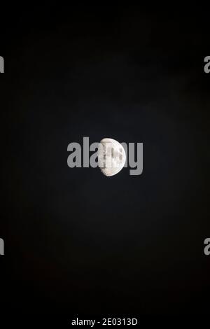 Ein wachender, wuchtiger Mond (zwischen der Hälfte und dem Dreiviertel) in einem dunklen Nachthimmel. Hochformat Stockfoto