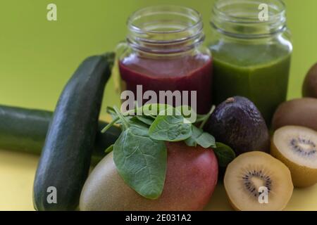 Nahaufnahme von Smoothies mit frischen Kiwis, Spinat, Zucchini und Avocado.gesunde grüne und rote Detox-Getränke in Einmachglas.. Stockfoto