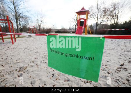 29. Dezember 2020, Thüringen, Altenburg: Mit rot-weißem Schutzband und einem Schild 'Spielplätze geschlossen' ist dieser Spielplatz geschlossen. Im Altenburger Land gelten seit 27.12.20 auch tagsüber Sperrungen. Draußen sind die Bewohner des Bezirks nur mit gutem Grund erlaubt. Foto: Bodo Schackow/dpa-Zentralbild/dpa Stockfoto