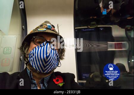 Selfie-Selbstporträt eines Mannes mittleren Alters mit Gesichtsmaske In der Londoner U-Bahn mit einem Warnschild Covid-19 Pandemie Stockfoto