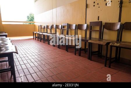 Nicht verwendete student Stuhl store vor der defekten Tür eines alten Klassenzimmer Stockfoto
