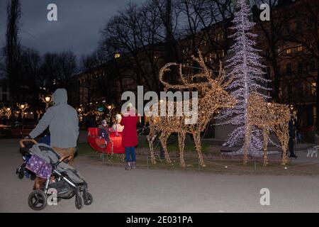 Helsinki, Finnland 29. Dezember 2020 traditioneller dekorativer Weihnachtsbaum und Rentier mit Schlitten auf der Bulvardi Street machen die Menschen Fotos in der Nähe. Hochwertige Fotos Stockfoto