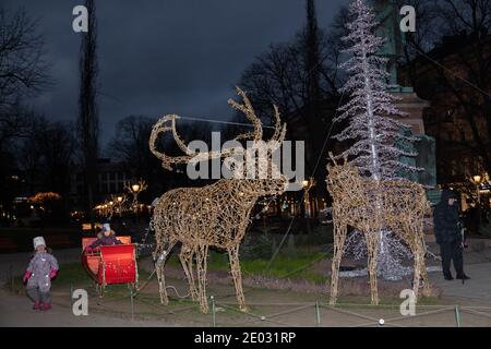 Helsinki, Finnland 29. Dezember 2020 traditioneller dekorativer Weihnachtsbaum und Rentier mit Schlitten auf der Bulvardi Street machen die Menschen Fotos in der Nähe. Hochwertige Fotos Stockfoto