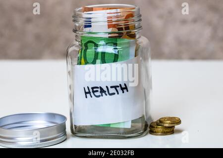 Komposition mit Spargeld Banknoten in einem Glas mit Text Gesundheit. Konzept der Investition und halten Geld, Nahaufnahme isoliert. Stockfoto