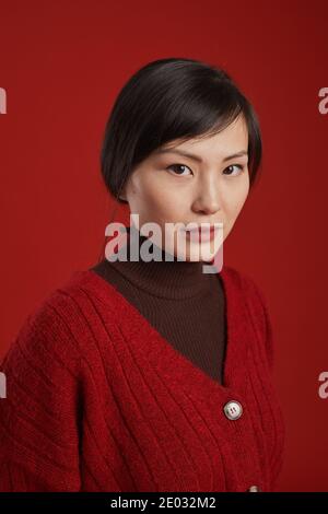 Nahaufnahme Porträt von charmanten asiatischen Frau trägt stilvolle Strickpullover Blick auf Kamera, roten Hintergrund Stockfoto