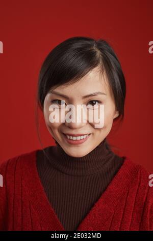 Nahaufnahme Studio Porträt der schönen reifen chinesischen Frau lächelt an der Kamera, roter Hintergrund Stockfoto
